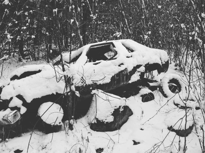 an old junked car in the woods, covered in snow