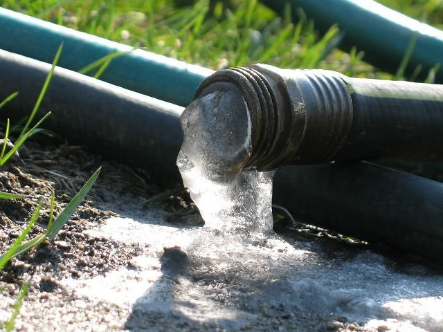 a garden hose with frozen water spilling out of it