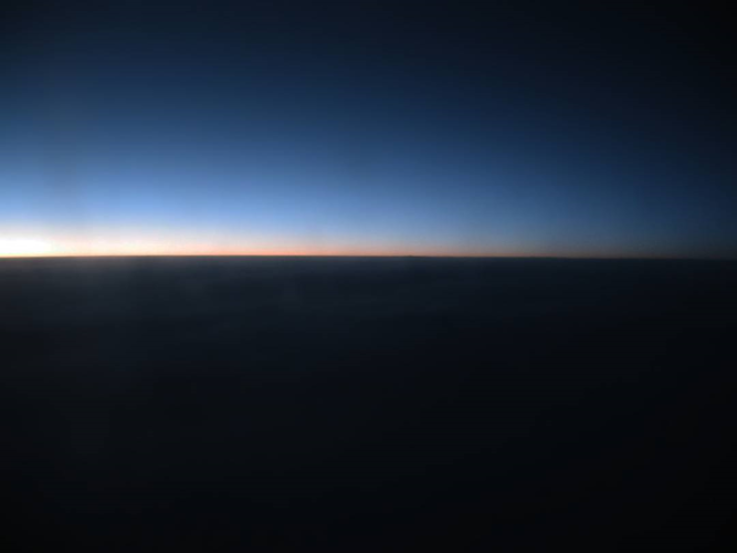 a high-altitude perspective of the sun just starting to come up over a distant horizon