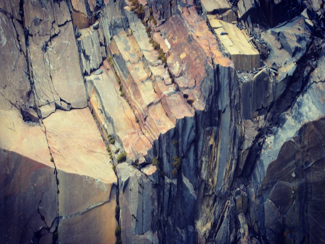 sharp and layered rock with bits of moss growing in the cracks between the sections